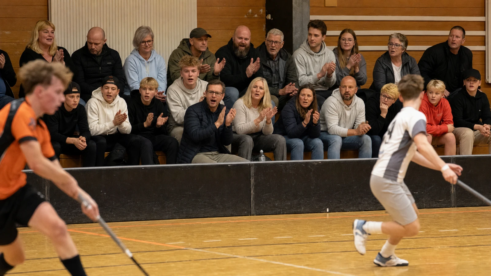 Läktaren under en match där ett tjugotal åskådare i olika åldrar applåderar och lutar sig framåt
