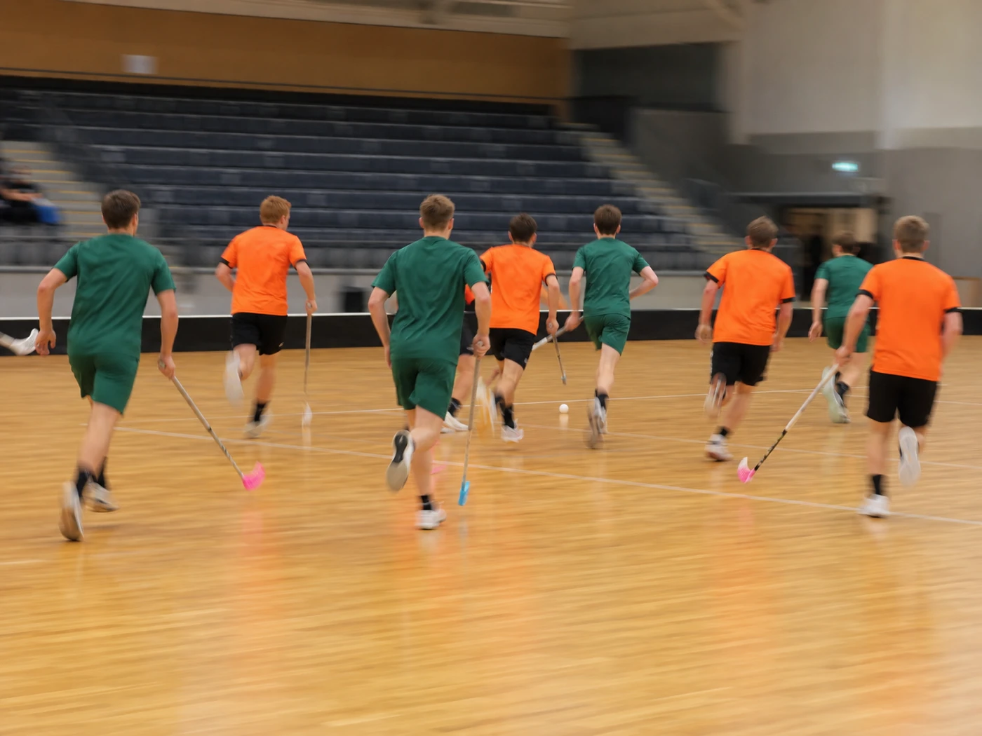 Innebandyspelare i rörelse på avstånd i en sporthall