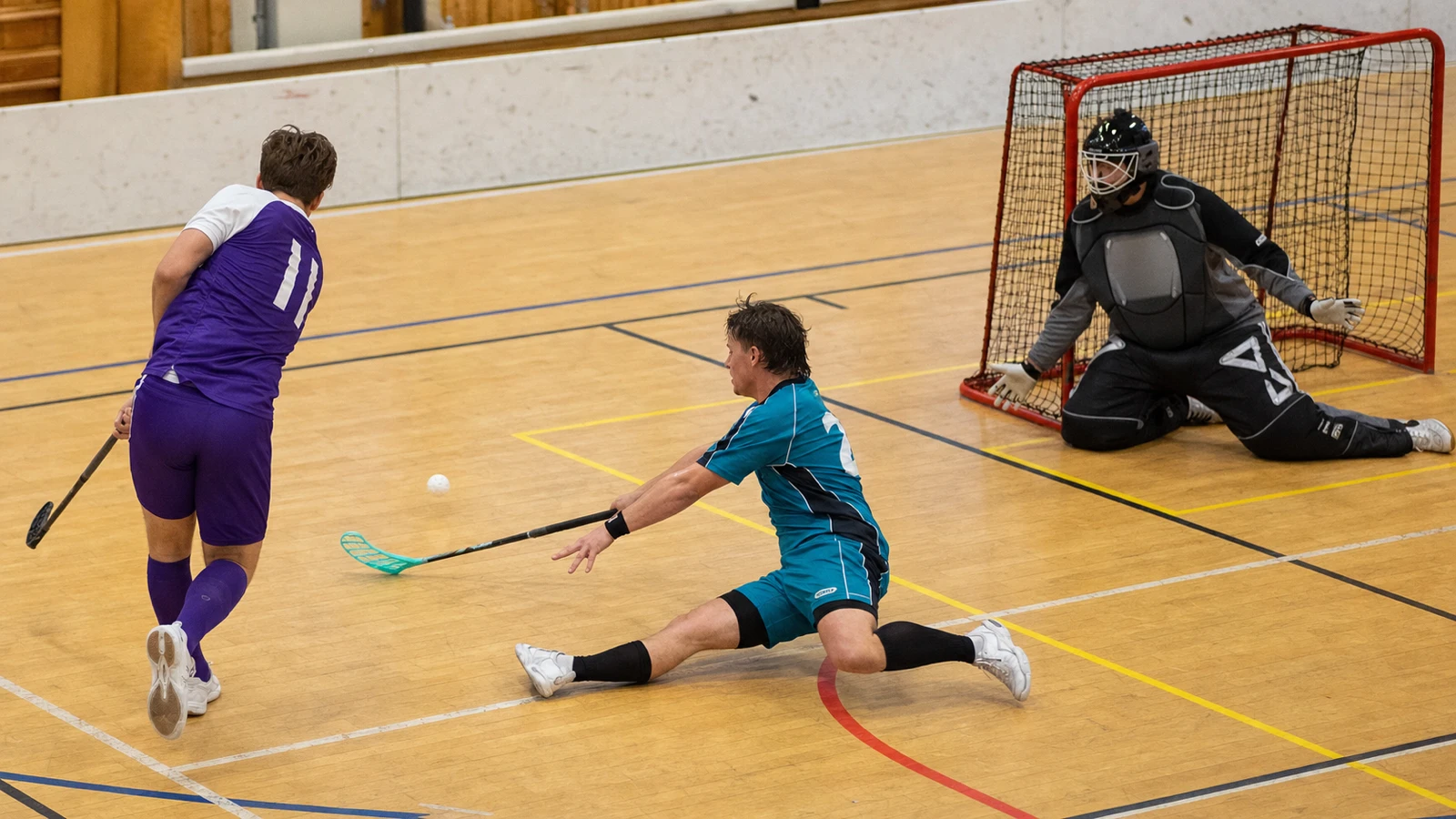 Från ett högt hörn skjuter en spelare från zonens topp medan en försvarare slänger sig för att blockera